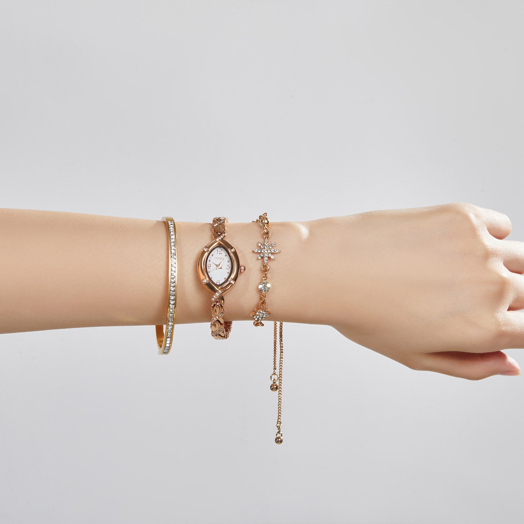 Woman's wrist showing a sophisticated layered look with the TIME100 Chelsea watch and jewelry bracelets Gold - Time100
